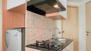 Een compacte keuken met een roestvrijstalen koelkast, een gasfornuis en een spoelbak.