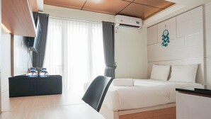 Een moderne hotelkamer met een bed, een bureau, een stoel, een televisie en een airconditioning.