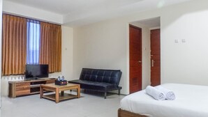 A hotel room with a bed, a sofa, a TV, and a coffee table.