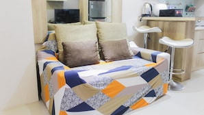 A compact bedroom with a bed, two pillows, a small kitchenette, and a bar stool. - Comfortable Fully Furnished 2BR Bassura City Apartment (Jakarta)
