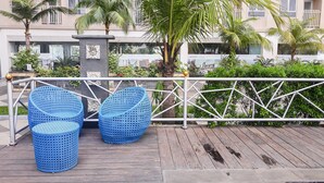 Une terrasse en bois avec des chaises en osier bleu et une rambarde en métal.