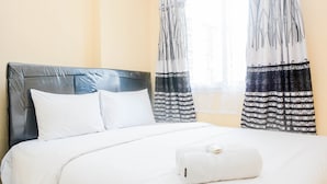 A neatly made bed with white linens, a grey headboard, and a white towel on the bed. - Comfy 2BR Mutiara Bekasi Apartement (Bekasi)