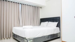 A neatly made bed in a room with a large window and curtains. - Comfy Studio at The Springlake Summarecon Apartment (Bekasi)