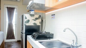 A compact kitchenette with a refrigerator, a stove, and a sink. - Relaxing Studio at Springlake Summarecon Bekasi Apartment (Bekasi)