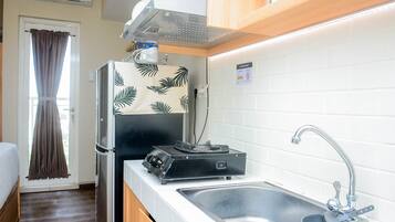 A compact kitchenette with a refrigerator, a stove, and a sink.