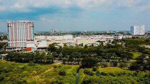 A high-rise hotel with multiple floors, surrounded by greenery and other buildings in the background. - Relaxing Studio at Springlake Summarecon Bekasi Apartment (Bekasi)