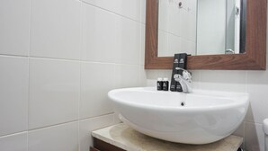 A bathroom with a white sink, a wooden-framed mirror, and a toilet. - Comfort Studio Cervino Village Apartment near Casablanca (Jakarta)
