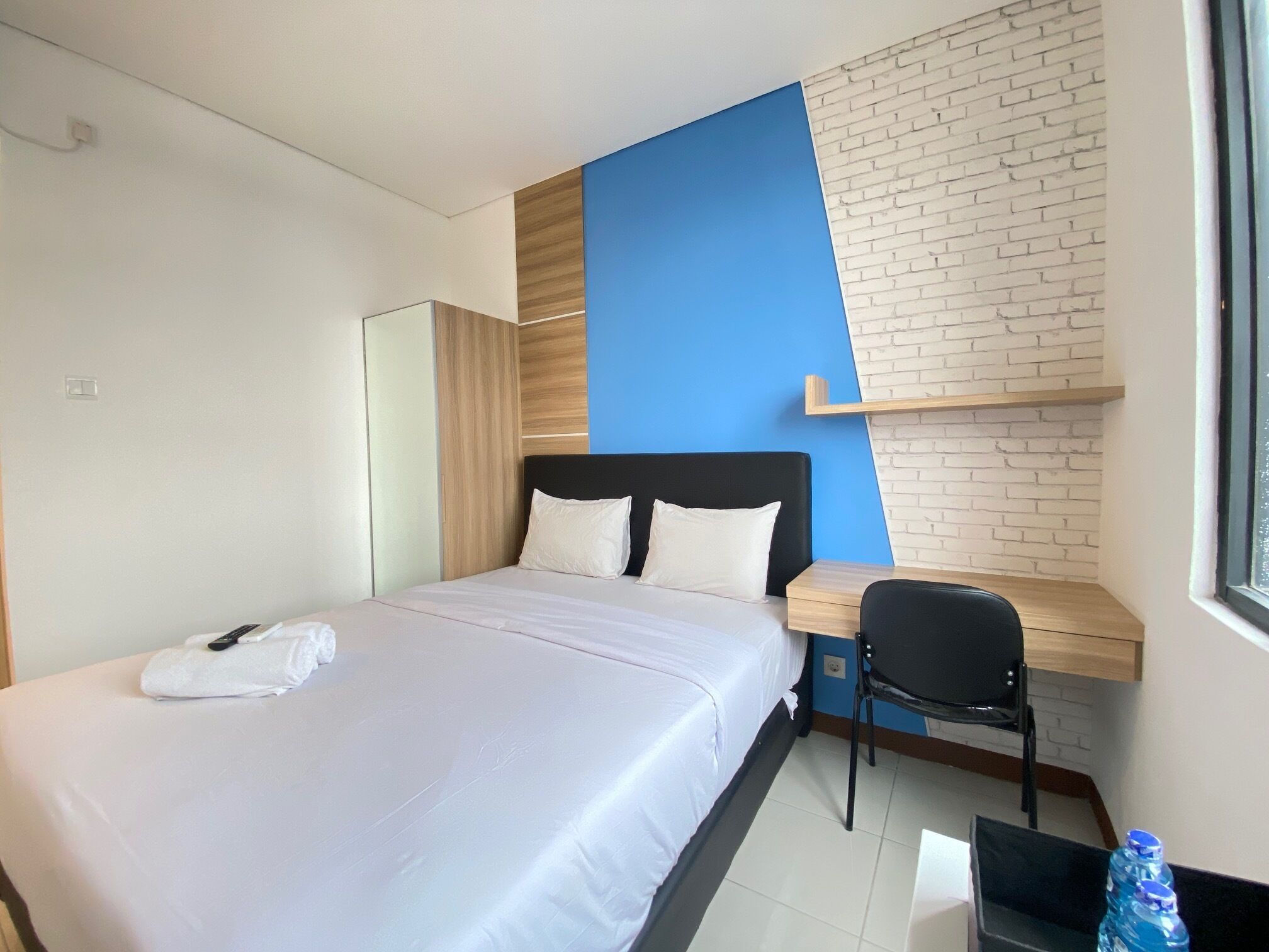 Una habitación de hotel con una cama, un escritorio, una silla y un ventanal.