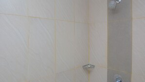 A bathroom with beige tiles and a shower area.