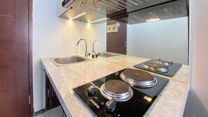 A modern kitchen with a double sink, stainless steel faucet, and a black induction cooktop. - Luxurious & Cozy 2BR Gateway Pasteur Apartment near Exit Toll (Cimahi)