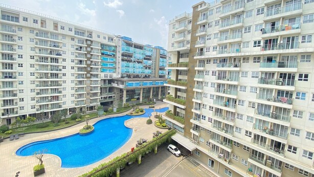 A high-rise residential building with multiple balconies, a central swimming pool, and a landscaped area with pathways. - Luxurious & Cozy 2BR Gateway Pasteur Apartment near Exit Toll (Cimahi)