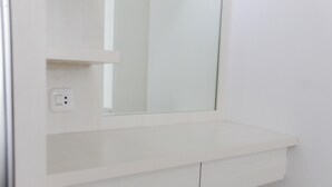 A white wall with a mirror and a shelf. - Homey and Cozy 2BR Bassura City Apartment near Mall (Jakarta)