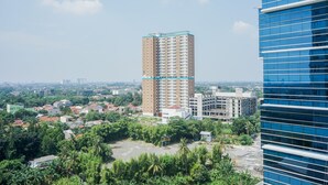 A high-rise building with a modern design, surrounded by greenery and other buildings. - Minimalist and Cozy Studio Apartment at Tuscany Residences (South Tangerang)