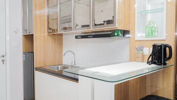 Een moderne keuken met een glazen aanrecht, een roestvrijstalen spoelbak en een ingebouwde vaatwasser.