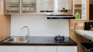 A modern kitchen with a stainless steel sink, a gas stove, and glass-front cabinets. - Minimalist and Cozy Studio Apartment at Tuscany Residences (South Tangerang)