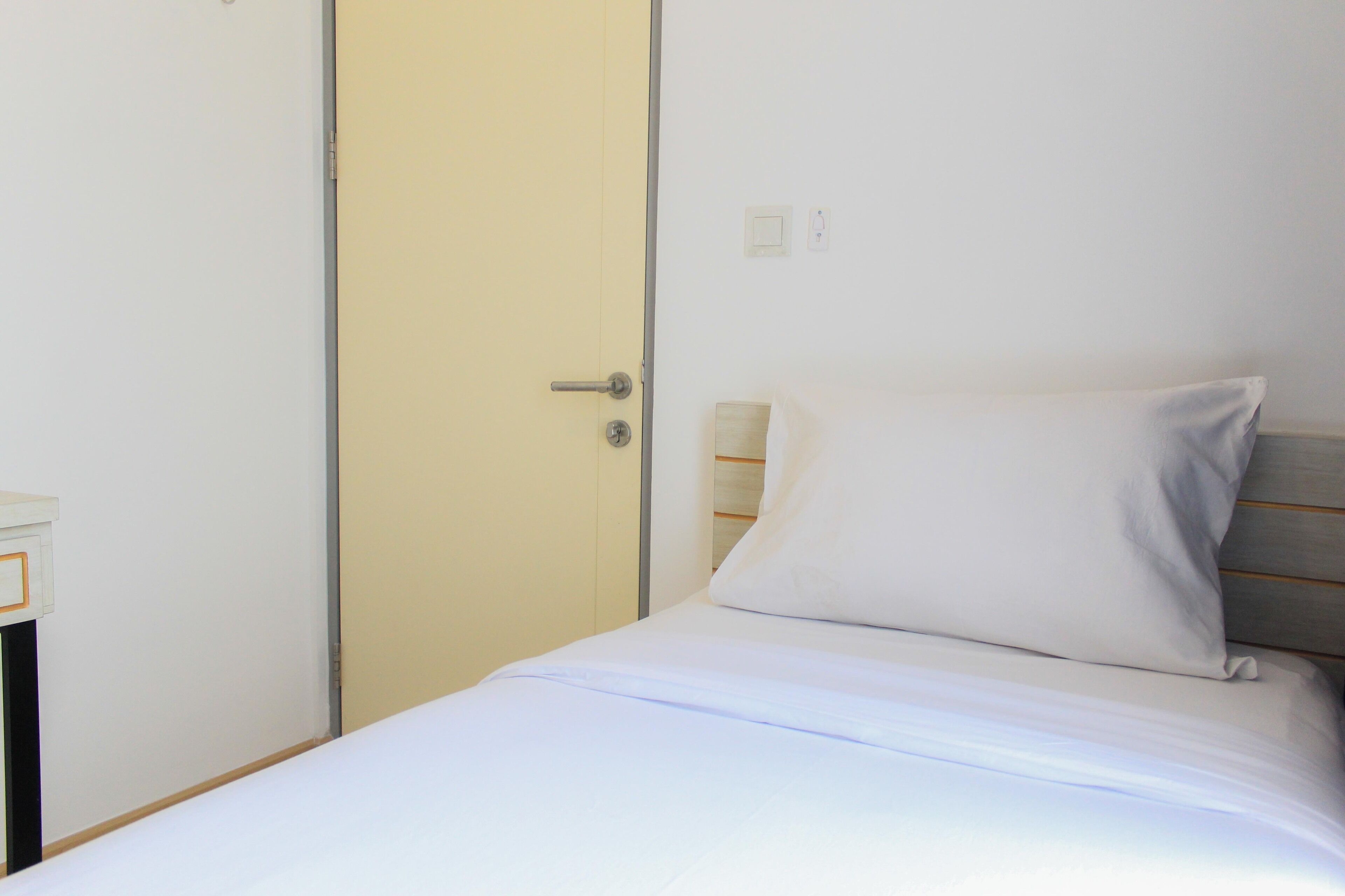 A bedroom with a bed, a door, and a bedside table.