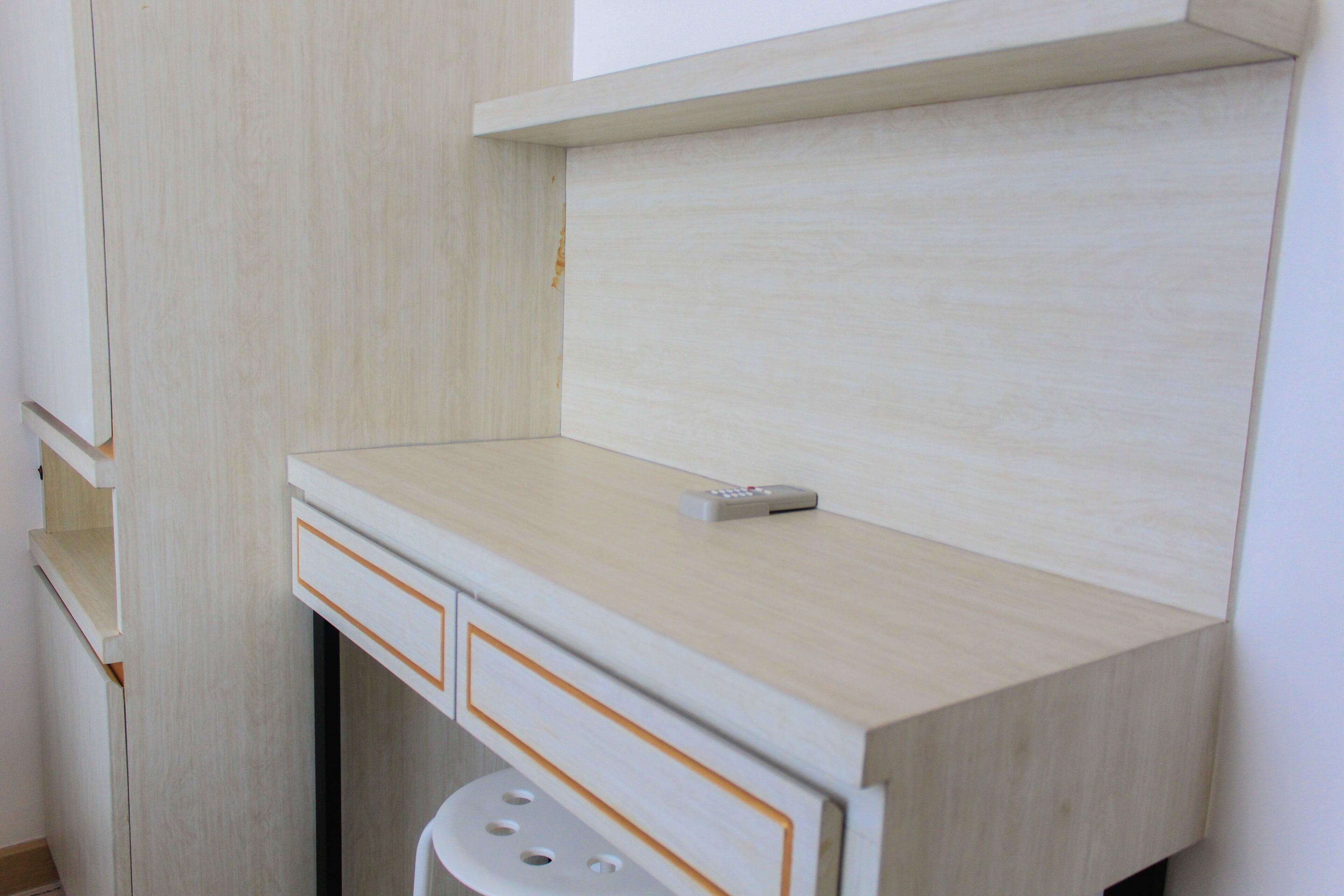 Ein kleiner, heller Holztisch mit einer Fernbedienung darauf.