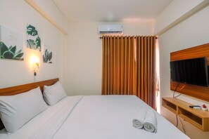 A hotel room with a bed, a TV, an air conditioner, and a curtain. - Comfy Studio at Bogorienze Apartment near The Jungle Waterpark (Bogor)