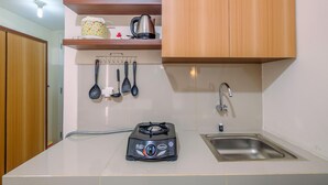 A kitchen with a gas stove, sink, and wooden cabinets. - Comfy Studio at Bogorienze Apartment near The Jungle Waterpark (Bogor)
