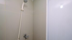 A bathroom with a shower, a toilet, and a door.