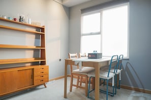 A room with a wooden desk, two chairs, a window, and a shelf with various items. - Luxurious 1BR Apartment at Belmont Residence (Jakarta)