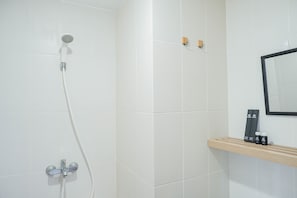 A shower with a handheld showerhead and a wall-mounted faucet. There is a wooden shelf with toiletries. - Luxurious 1BR Apartment at Belmont Residence (Jakarta)