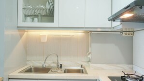 Een moderne keuken met een roestvrijstalen spoelbak, een gasfornuis en een afdruiprek boven de spoelbak.