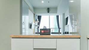 Een moderne keuken met een marmeren aanrecht, een klok aan de muur en uitzicht op een gebouw.