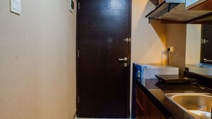 Une petite cuisine avec une porte sombre, un évier en acier inoxydable et un four à micro-ondes.