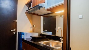 Une cuisine de taille réduite, équipée d’un évier, de placards et d’un four à micro-ondes.