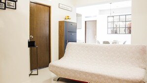 Um quarto com sofá, armário, porta e uma placa com a mensagem 'welcome home'.