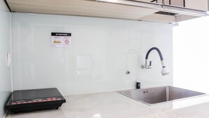 Cozinha moderna com micro-ondas embutido, pia de aço inoxidável e torneira.