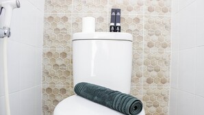 Casa de banho com painel de azulejos hexagonais e uma toalha no assento.