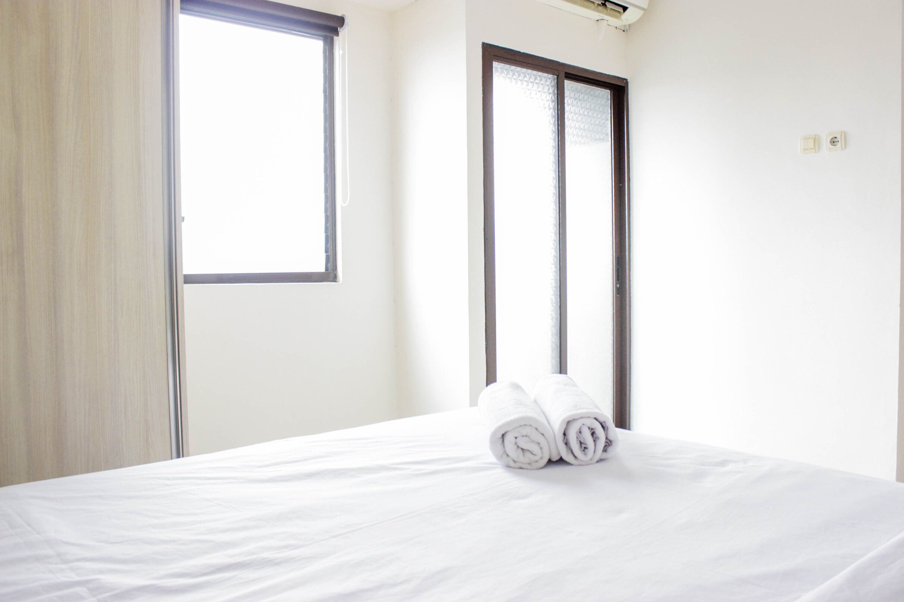 A hotel room with a bed, a window, and a door.