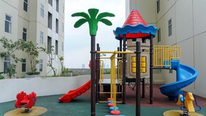 Un parque infantil con toboganes y estructuras para escalar, rodeado de edificios.