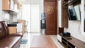Una sala de estar moderna con un sofá de cuero marrón, una mesa de centro de madera, un televisor sobre un mueble de madera y un dispensador de agua.