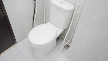 Un inodoro blanco en un baño con azulejos blancos en las paredes y el suelo.