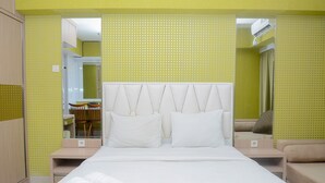 A hotel room with a large bed, two bedside tables, a sofa, and a mirror. - Fully Furnished with Comfortable Design Studio Apartment H Residence (Jakarta)