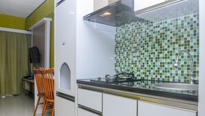 A kitchen with white cabinets, a gas stove, a sink, and a tiled backsplash. - Fully Furnished with Comfortable Design Studio Apartment H Residence (Jakarta)