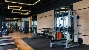 A gym with treadmills, weight machines, and a mirrored wall.