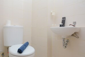 Et badeværelse med toilet, vask og et håndklæde på toilettet.