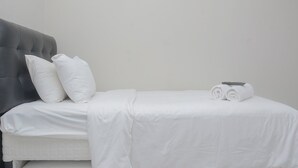 A neatly made bed with white linens and two rolled towels on the side. - Alluring Studio at Lagoon Apartment near Bekasi Town Square (Bekasi)