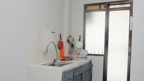 A compact kitchen with a sink, a dish rack, and a window with a frosted glass door. - Alluring Studio at Lagoon Apartment near Bekasi Town Square (Bekasi)