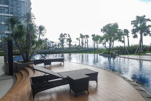 A poolside area with lounge chairs and a wooden deck. - Modern Luxurious Studio Room at Anderson Supermall Mansion Apartment (Surabaya)
