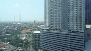 A high-rise building with multiple floors, surrounded by other buildings and greenery. - Modern Luxurious Studio Room at Anderson Supermall Mansion Apartment (Surabaya)