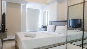 A modern hotel room with a large bed, a flat-screen TV mounted on the wall, and a large mirror reflecting the room. - Modern Luxurious Studio Room at Anderson Supermall Mansion Apartment (Surabaya)