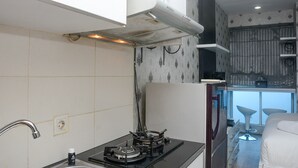 A compact kitchen with a gas stove, a built-in oven, and a microwave. There is a window providing a view of the outside.