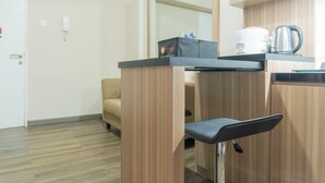 A compact hotel room with a kitchenette, a sofa, and a small table with a kettle.