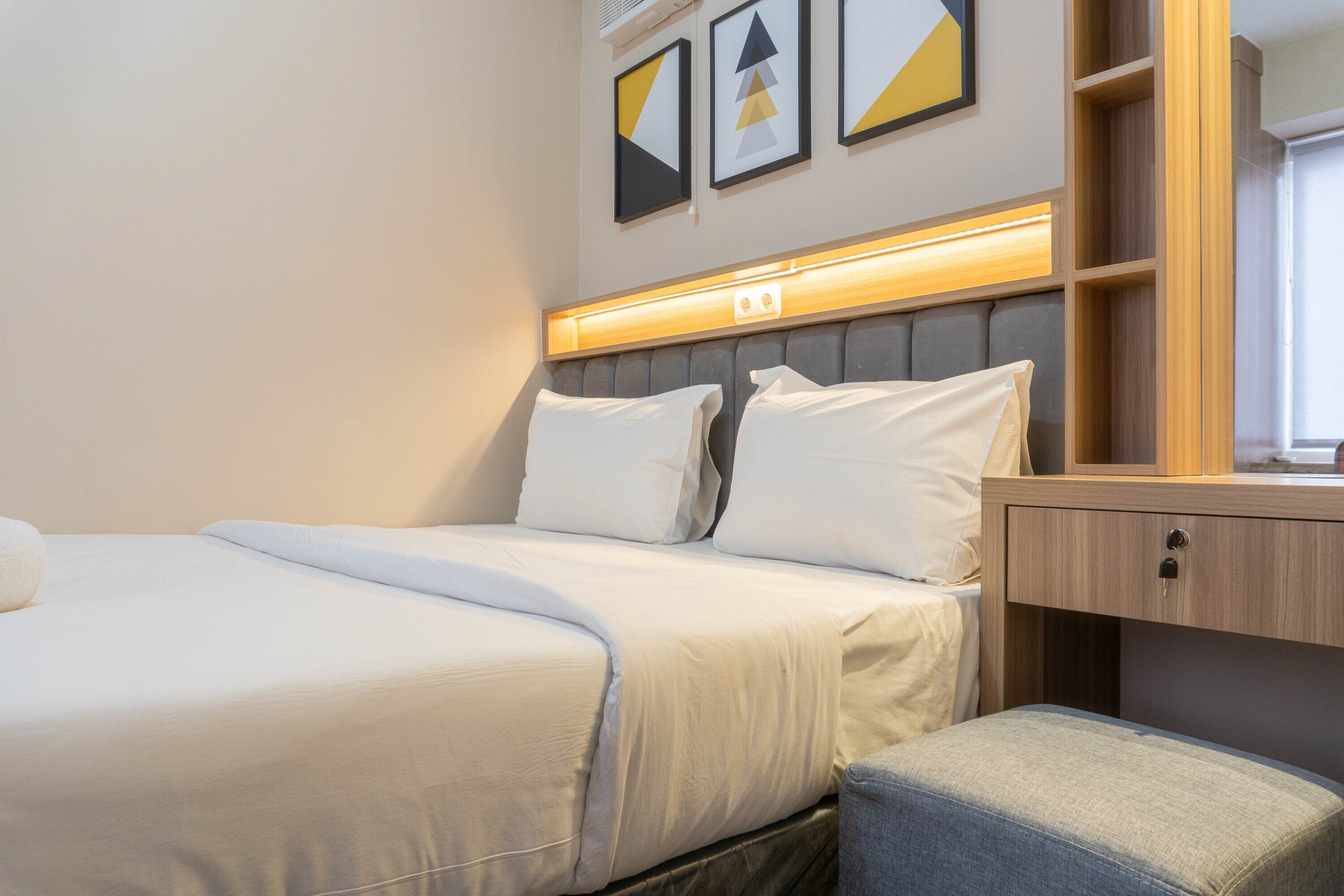 Habitación de hotel ordenada con una cama, una mesita de noche y una pequeña zona de estar.