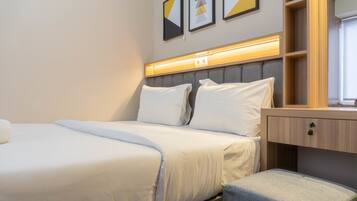 Habitación de hotel ordenada con una cama, una mesita de noche y una pequeña zona de estar.